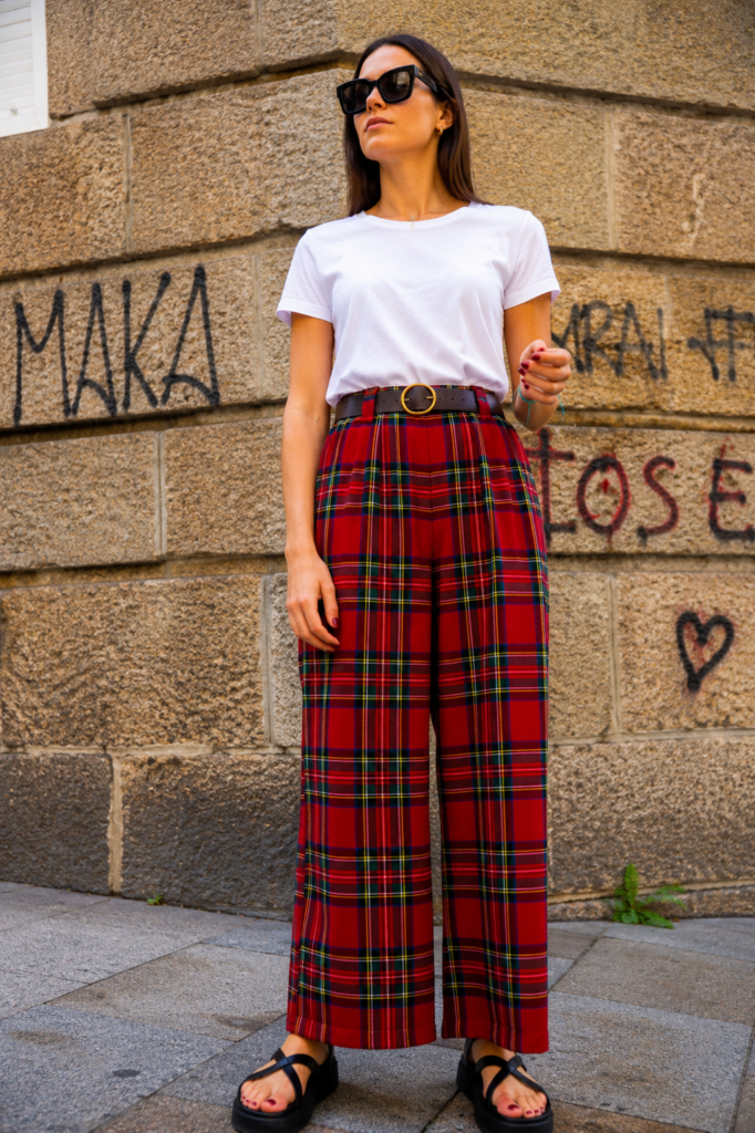 Modelo vistiendo el Pantalón Escocés Rojo de pierna ancha con estampado tartán rojo y cintura alta.