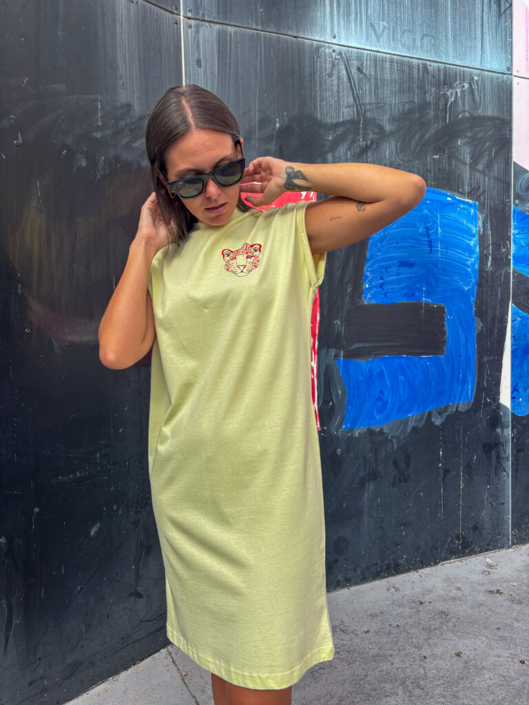 Modelo luciendo el Vestido Encantadora amarillo con ilustración de un leopardo en el pecho.
