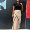 Falda midi beige con detalle diagonal en encaje negro, cintura elástica y caída fluida que puedes combinar con cualquier look.