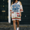 Mujer con vestido camiseta oversize blanco con estampado beisbol estilo urbano y casual, combinado con zapatillas deportivas.