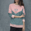 Sudadera bicolor rosa y verde con diseño geométrico y estampado central, combinada con pantalón oscuro en estilo casual.