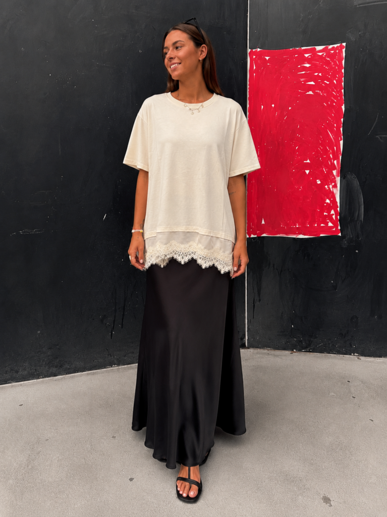Mujer luciendo la Camiseta Lace Touch beige con detalle de encaje en el bajo y corte oversize.
