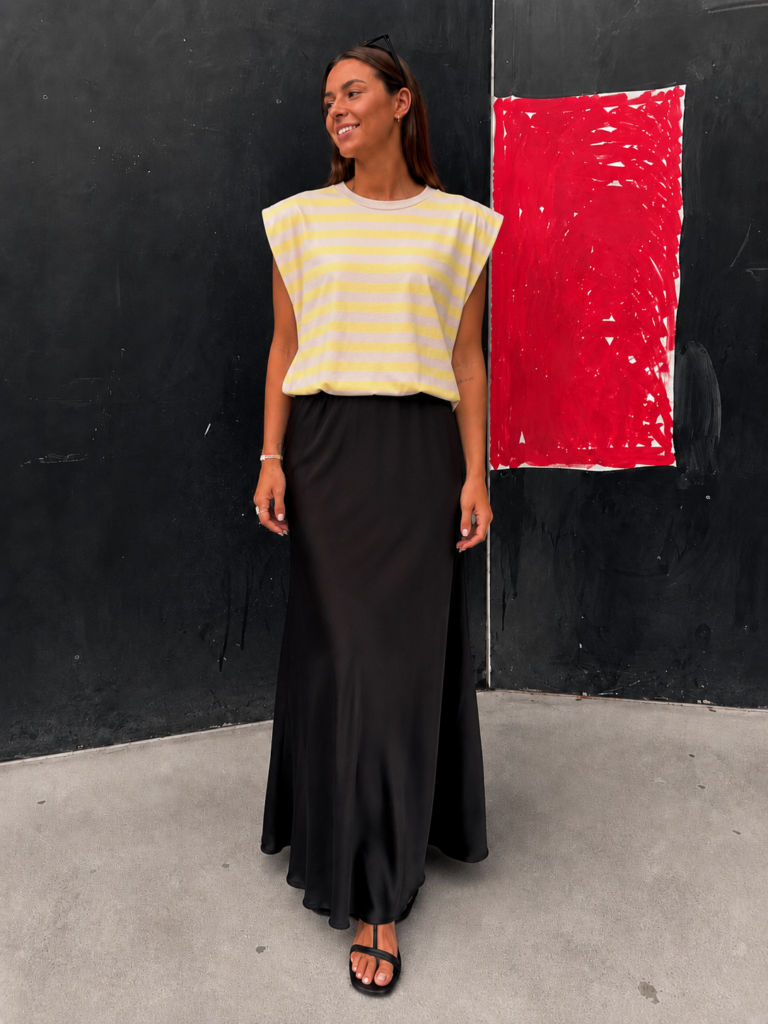 Mujer luciendo la Camiseta Lemon Breeze de rayas amarillas y beige con diseño relajado y hombros estructurados.