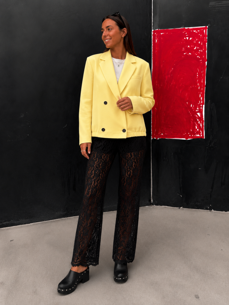 Mujer luciendo la Blazer Soleil en color amarillo pastel con diseño cruzado y estilo elegante.
