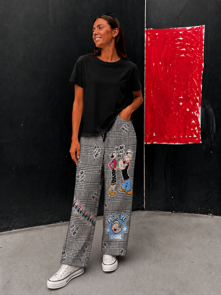 Modelo vistiendo el Pantalón Popeye de corte palazzo con estampado Príncipe de Gales e ilustraciones inspiradas en Popeye.