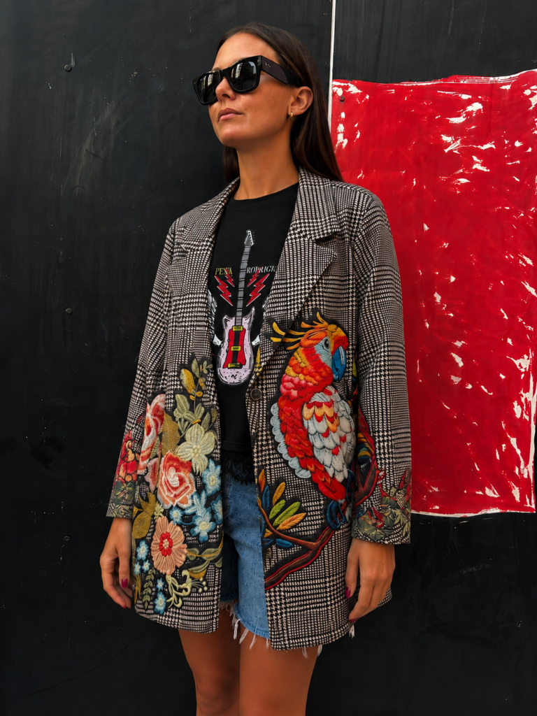 Mujer vistiendo la Blazer Guacamayo con estampado floral multicolor y gran guacamayo tropical sobre tejido de cuadro príncipe de Gales.
