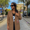 Modelo luciendo la Blazer Alma Camel con detalles de tachuelas metálicas y estampado exclusivo sobre fondo camel.