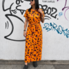 Vestido salvaje naranja con estampado animal print rosa y negro, corte midi con cinturón a juego, vista frontal sobre modelo.