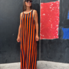 Vista completa de vestido largo sin mangas con estampado de rayas verticales en naranja y azul marino, de corte recto y tejido fluido.