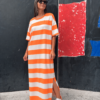 Mujer con vestido maxi sunset tipo camiseta de rayas horizontales naranja y blanco, combinado con zapatillas blancas.
