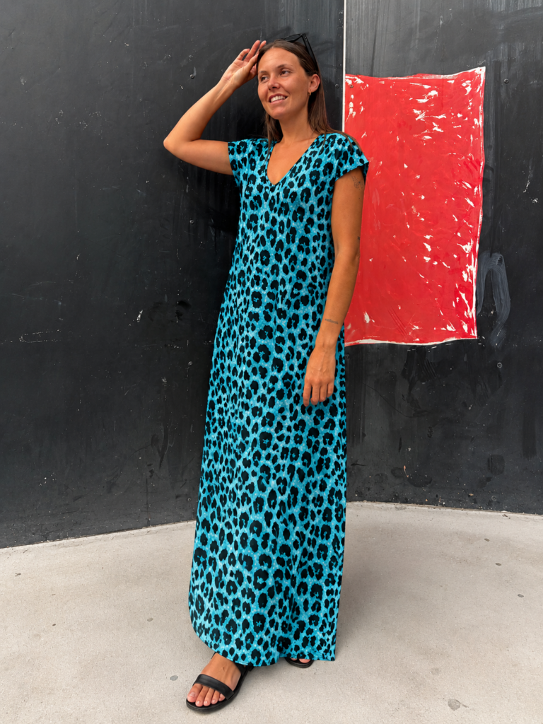 Mujer luciendo el Vestido Blue Leopard, un vestido maxi azul turquesa con estampado animal print y escote en V.