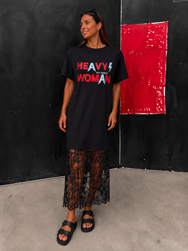Vestido camiseta oversize negro para mujer con estampado Heavy Woman en rojo y blanco y detalle de encaje floral semitransparente en el bajo.
