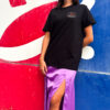 Falda midi satinada en color lila con caída fluida y acabado brillante, combinada con camiseta negra de estilo casual urbano con camiseta de la marca combinada