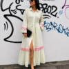 Modelo luciendo el Vestido Largo Lima de Pepa Rodríguez en color blanco con detalles bordados en amarillo flúor, borlas rosas y cinturón ajustable. Un vestido estilo boho en toda regla